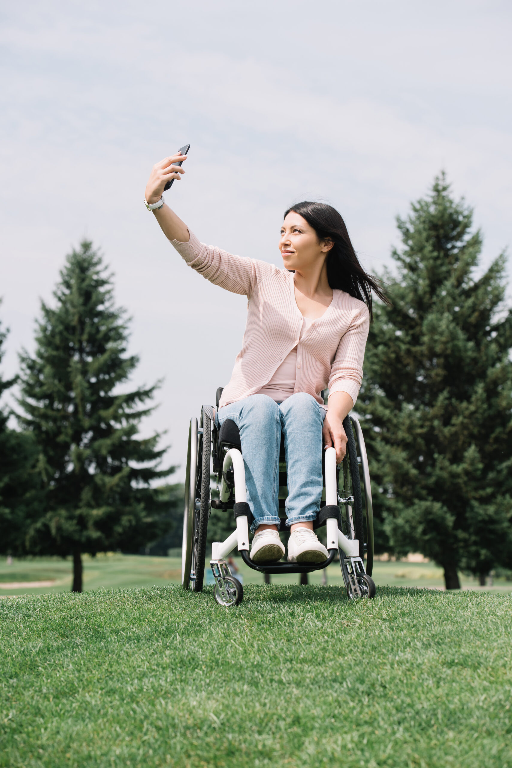 Young female in wheelchair outside, recording content
