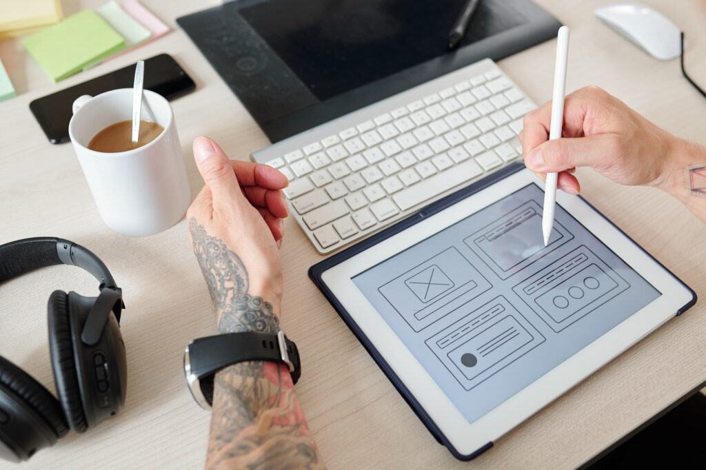 Designer working on tablet with a drawing pencil developing websites