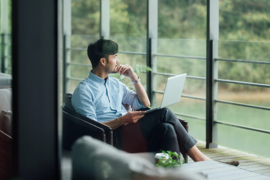 Asian businessman using laptop at office window - Image from Inkfire Limited