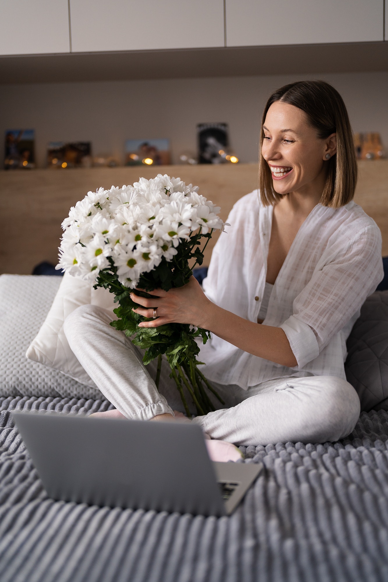Happy woman smiling holding a bunch of flowers with laptop in the forefront
