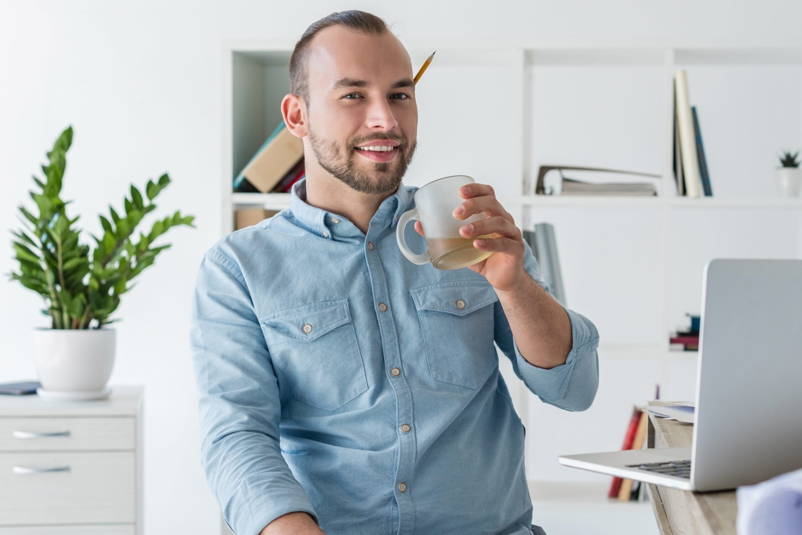 smiling disabled businessman in office, drinking coffee and looking at camera