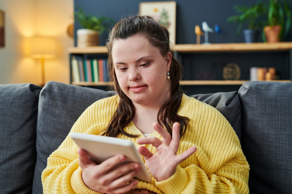 A woman sitting on a couch looking at a tablet