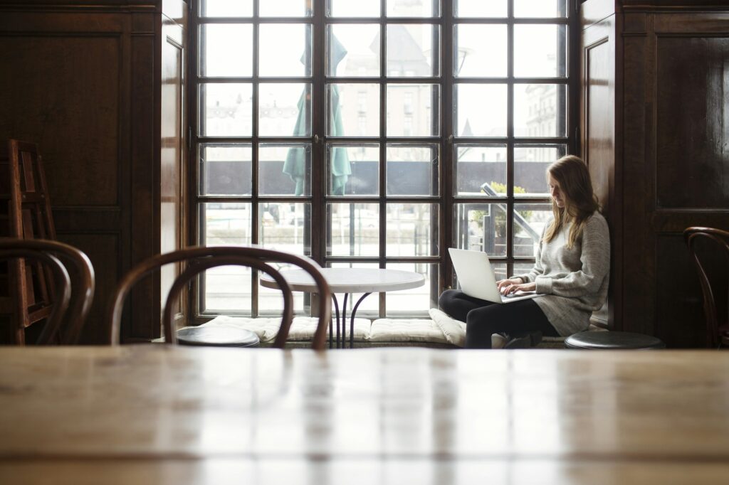 A woman in a coffee shop is deciding which is better - Microsoft 365 vs Google Workspace